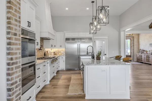 a kitchen with stainless steel appliances kitchen island granite countertop a sink stove and refrigerator