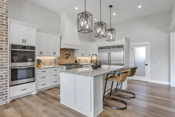 a kitchen with stainless steel appliances granite countertop a stove oven and white cabinets with wooden floor