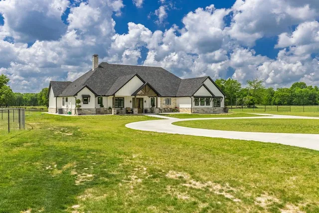 a view of a house with a big yard and large trees