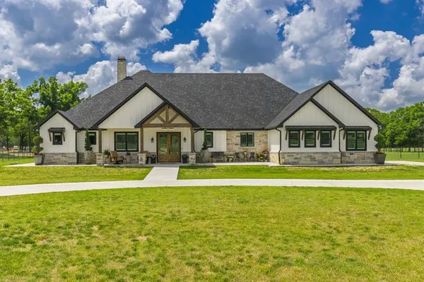 a front view of a house with swimming pool and trees in the background