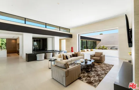 a kitchen with stainless steel appliances a stove a sink a refrigerator and couches