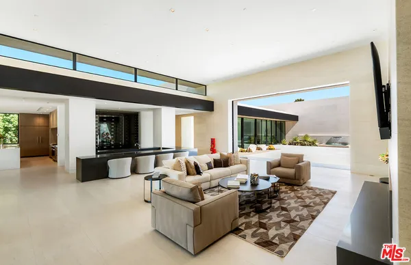 a kitchen with stainless steel appliances a stove a sink a refrigerator and couches
