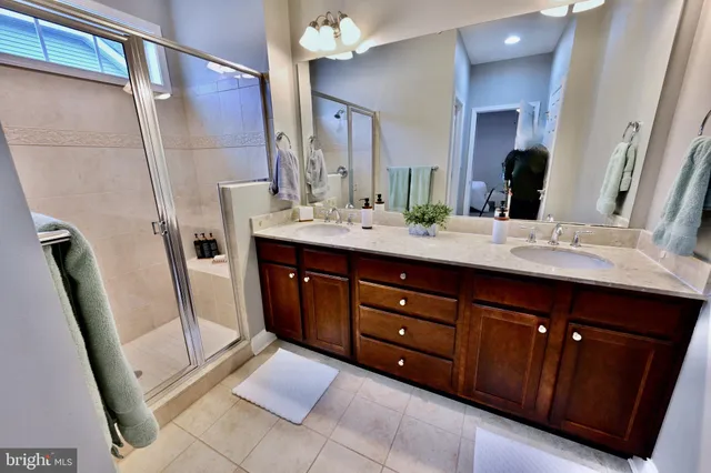 a spacious bathroom with a double vanity sink a mirror and a shower