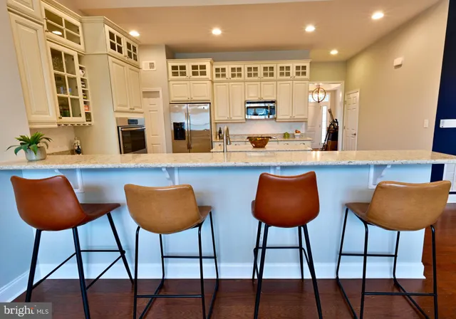 a kitchen with stainless steel appliances granite countertop a table chairs and a wooden floor