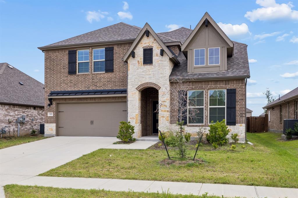 1303 Wheelwright Drive Forney, TX 75126 - Photo 10 of 39 Two-story residence featuring a brick and stone facade, arched entryway, and dark shutters
