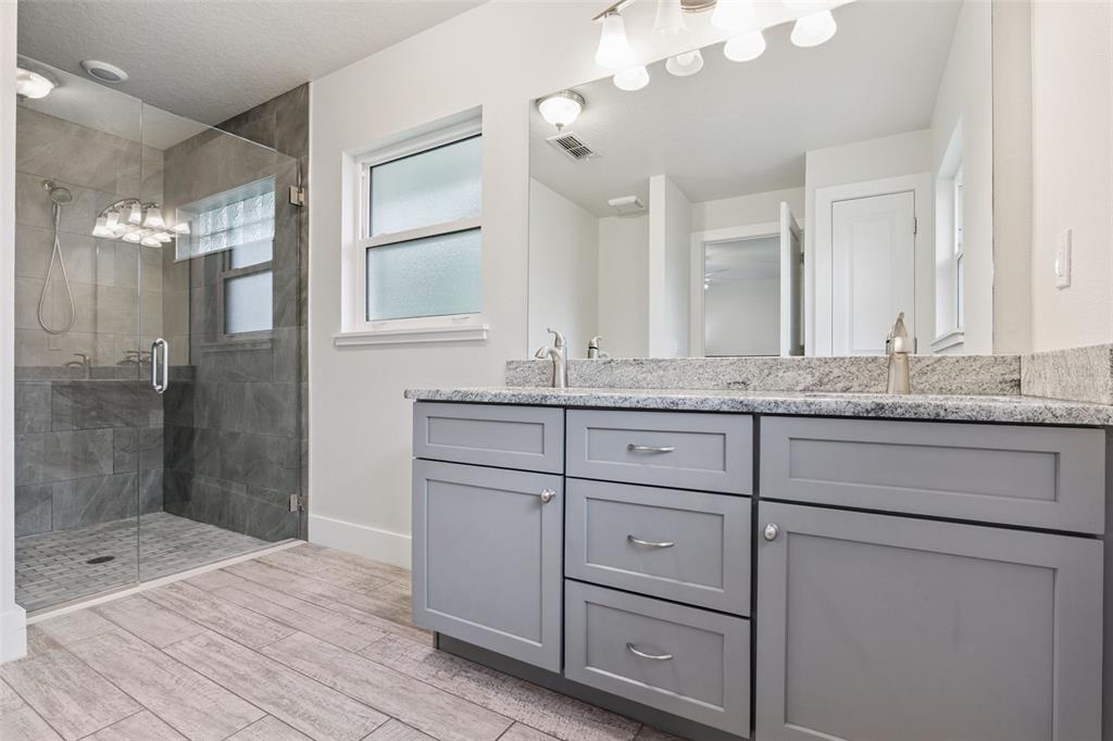 1049 Pinder Street Deltona, FL 32725 - Photo 12 of 20 a bathroom with a granite countertop sink a mirror and shower