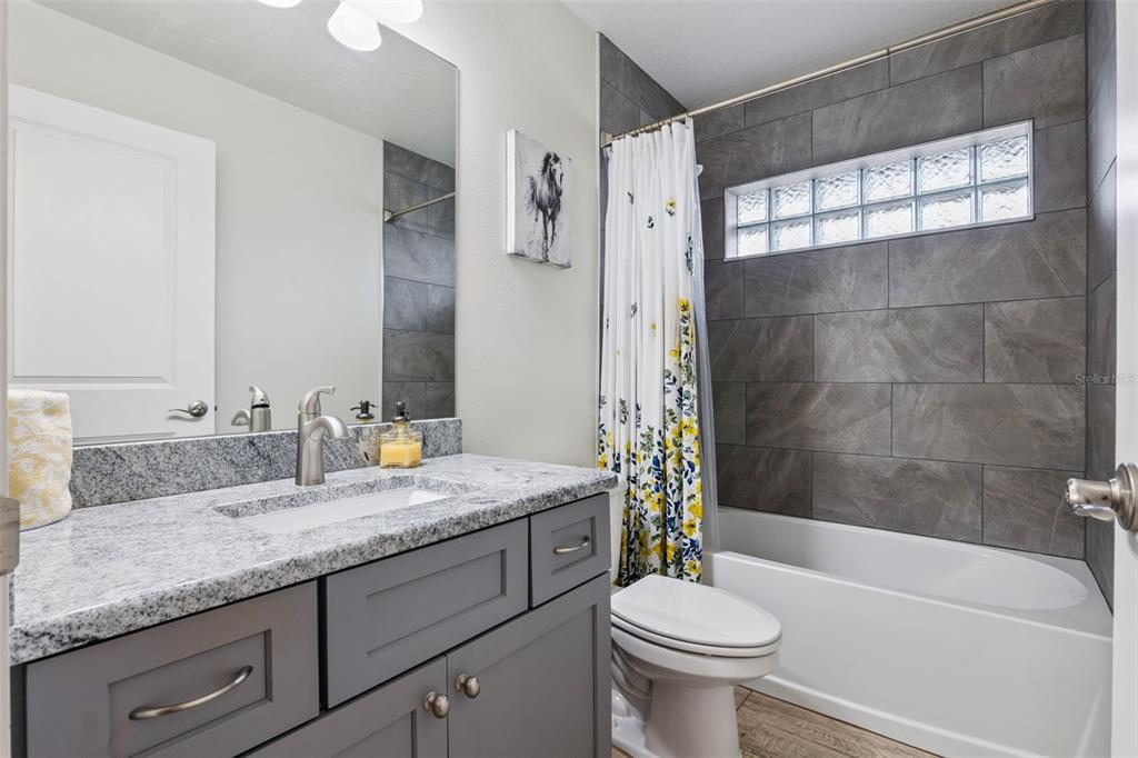 1049 Pinder Street Deltona, FL 32725 - Photo 18 of 20 a bathroom with a granite countertop sink a toilet a mirror and shower