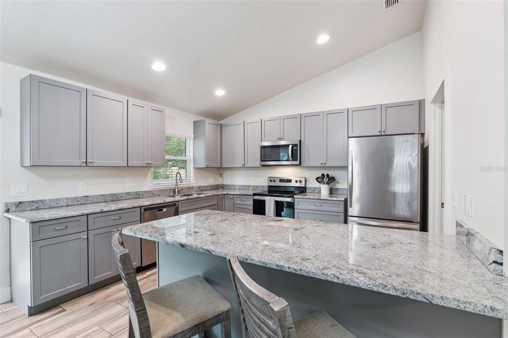 1049 Pinder Street Deltona, FL 32725 - Photo 8 of 20 a kitchen with stainless steel appliances granite countertop a sink refrigerator and cabinets