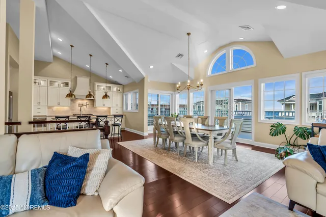 a kitchen with stainless steel appliances kitchen island granite countertop a stove a refrigerator a kitchen island a dining table and chairs with wooden floor