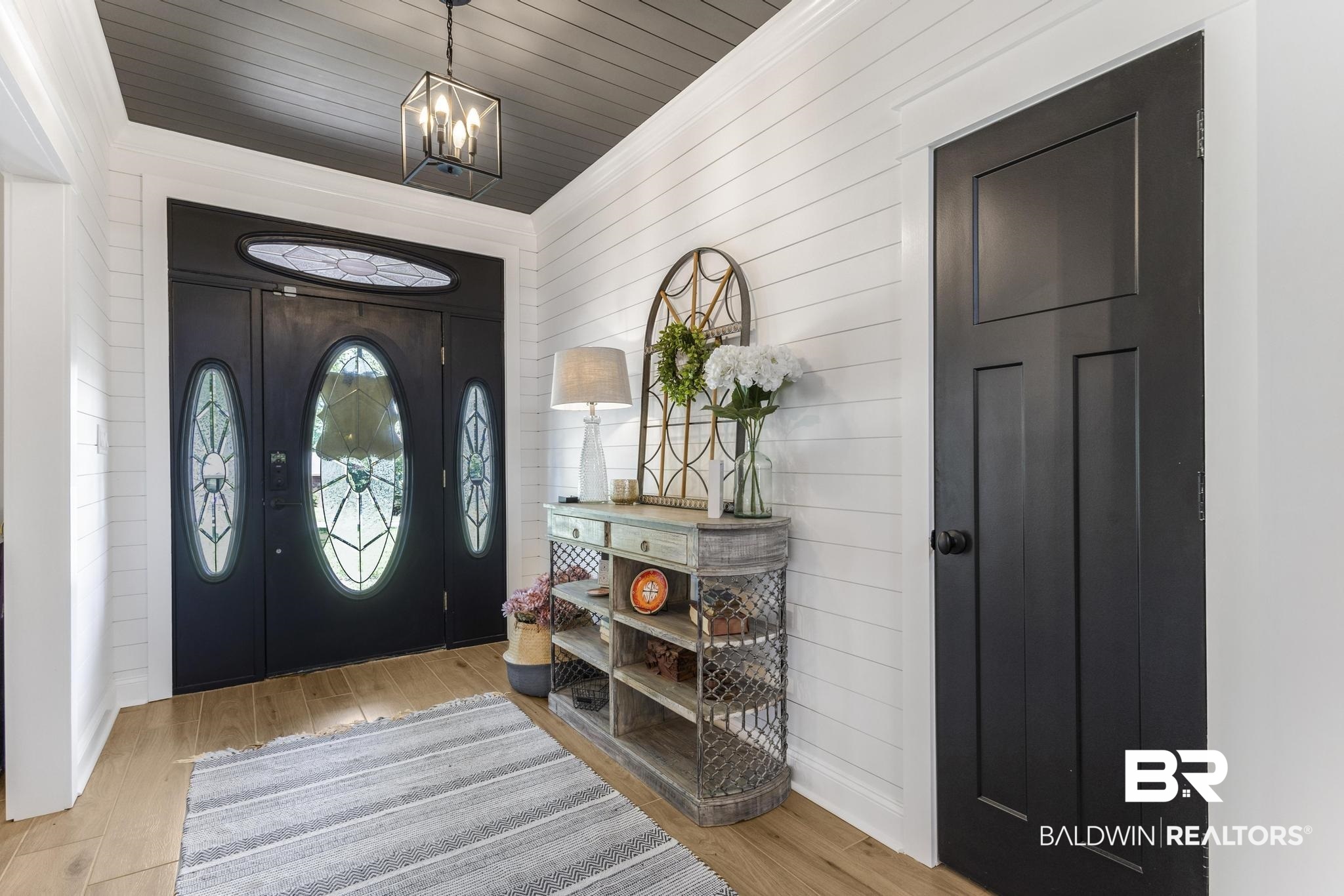 83 Caisson Trace Daphne, AL 36527 - Photo 7 of 63 Entryway featuring a black front door with decorative glass inserts, white shiplap walls, wood-finish flooring, and a dark paneled ceiling with a modern pendant light