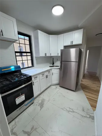 a kitchen with a stove a refrigerator and white cabinets