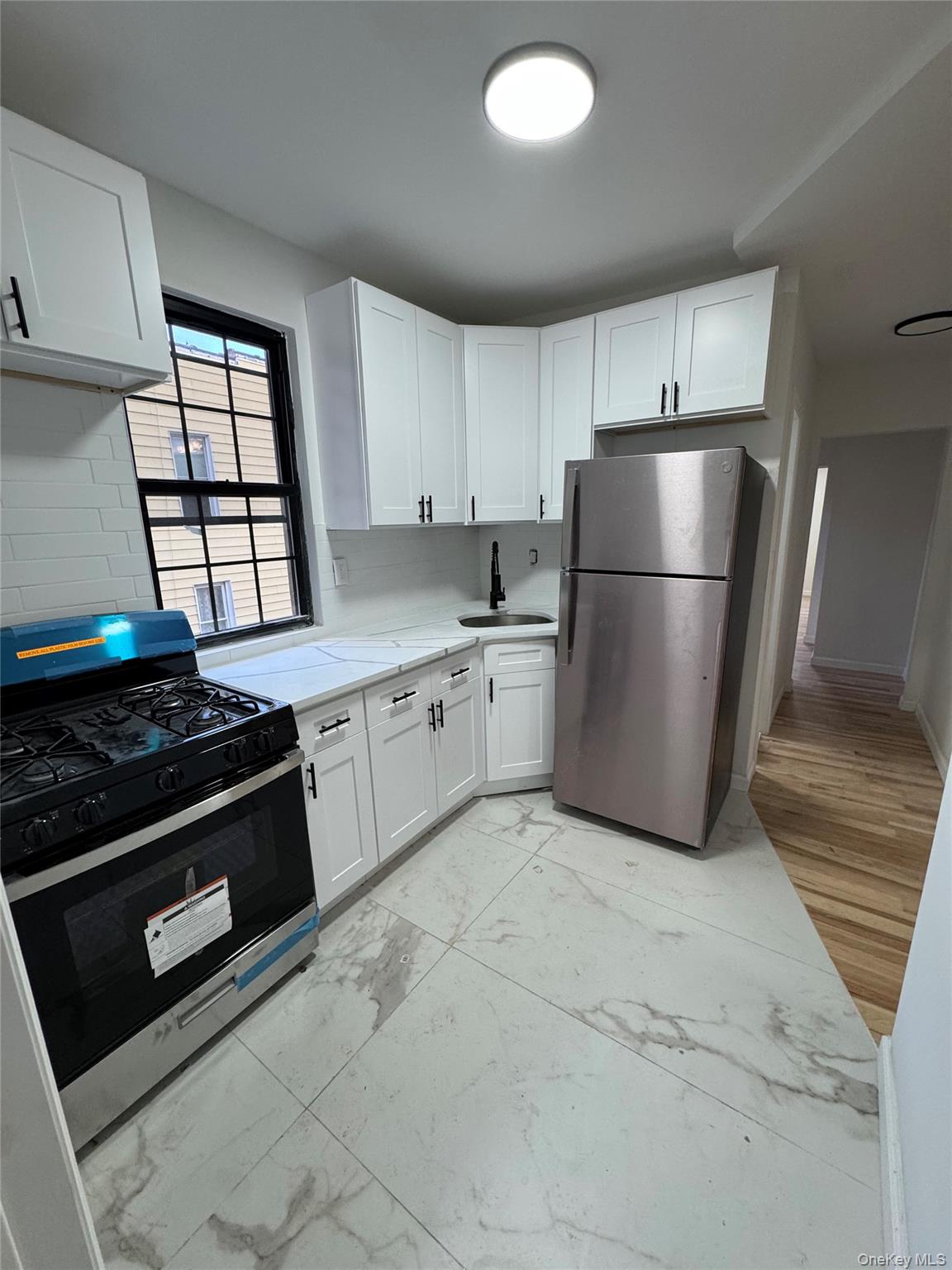 1827 Amethyst Street, Unit 2 Bronx, NY 10462 - Photo 5 of 9 a kitchen with a stove a refrigerator and white cabinets