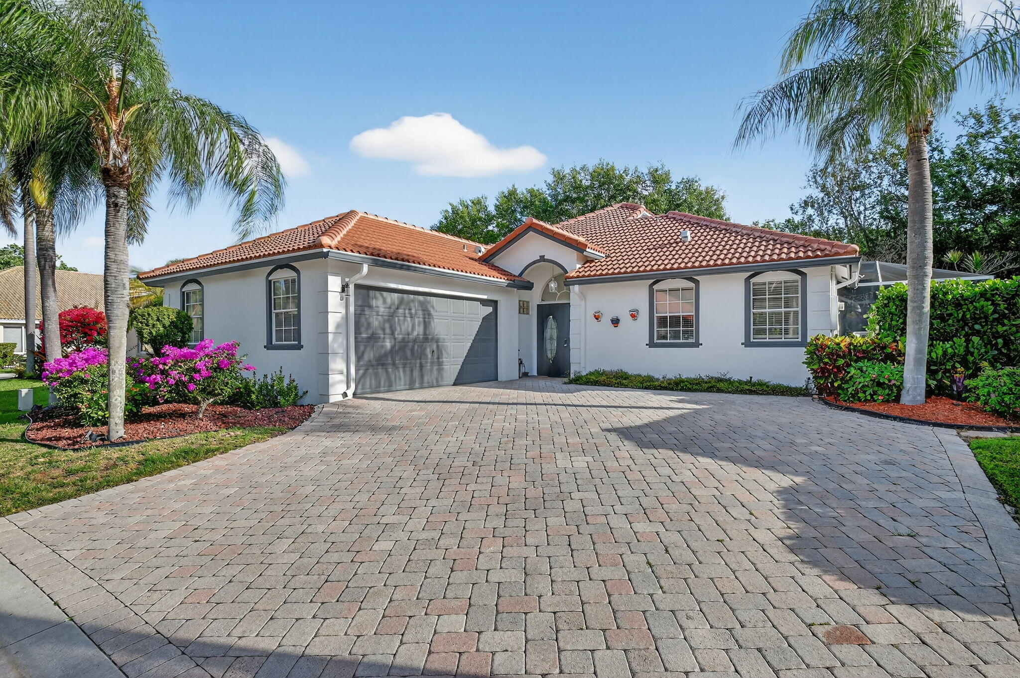front view of a house with a yard and palm trees