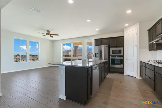 a large kitchen with stainless steel appliances a sink stove and refrigerator