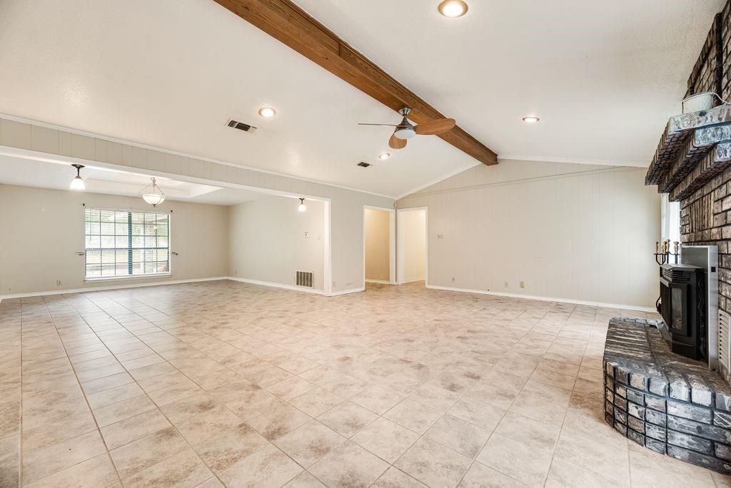 298 Butterfield Road Denison, TX 75021 - Photo 24 of 34 Spacious living area featuring neutral tile flooring, a vaulted ceiling with exposed wood beam, recessed lighting, and a brick fireplace