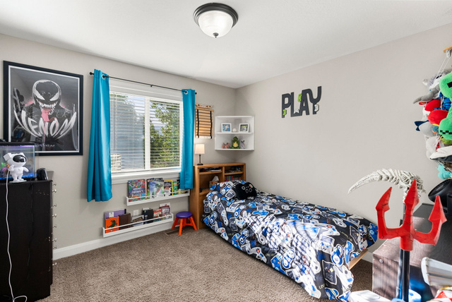 2485 South 1100th Street West Logan, UT 84321 - Photo 23 of 53 Carpeted bedroom featuring a large window with blinds, two white wall-mounted book ledges, and a ceiling-mounted light fixture