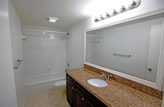 a bathroom with a granite countertop sink a mirror and a bathtub