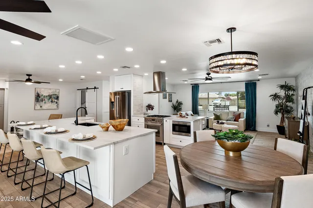 a dining room with stainless steel appliances kitchen island a table and chairs in it