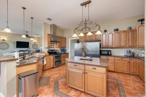 a kitchen with kitchen island granite countertop a sink stove and refrigerator