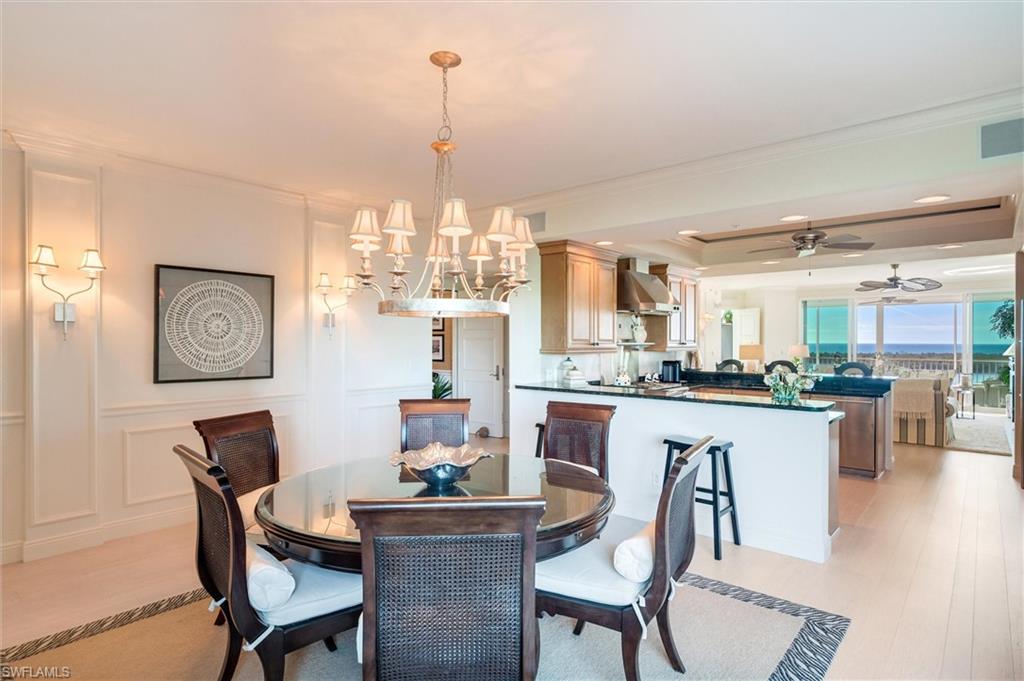 265 Indies Way, Unit 802 Naples, FL 34110 - Photo 11 of 50 a kitchen with a dining table chairs and white cabinets