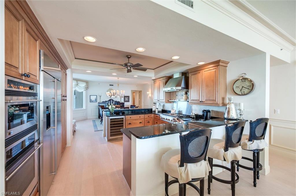 265 Indies Way, Unit 802 Naples, FL 34110 - Photo 12 of 50 a kitchen with stainless steel appliances a dining table chairs stove and cabinets