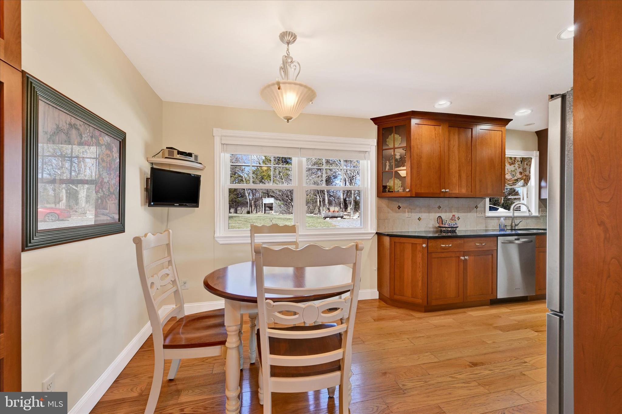 2524 Jennings Chapel Road Woodbine, MD 21797 - Photo 5 of 41 a kitchen with stainless steel appliances kitchen island granite countertop a stove a sink a microwave a dining table and chairs with wooden floor