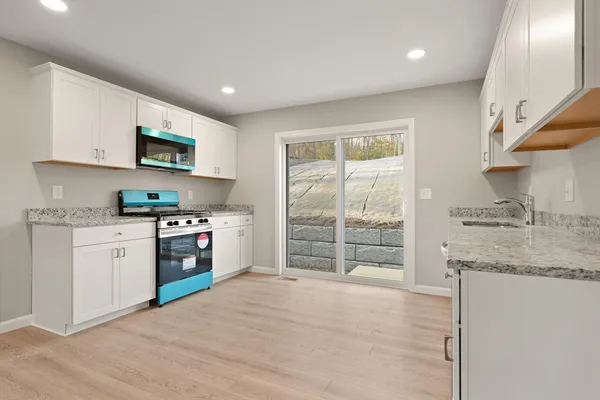 a kitchen with granite countertop a stove a sink and a refrigerator