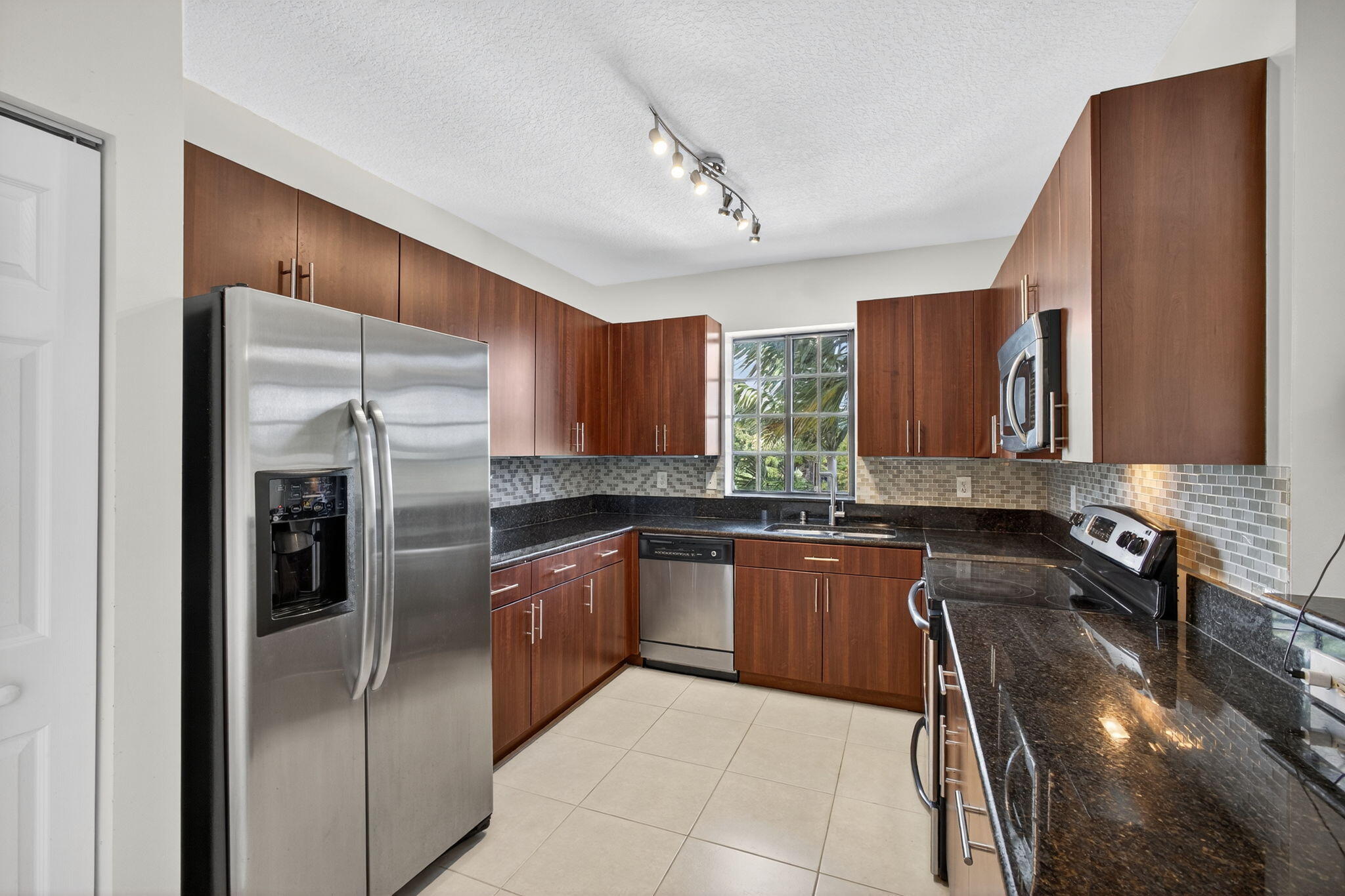 4907 Midtown Lane, Unit 1314 Palm Beach Gardens, FL 33418 - Photo 16 of 57 a kitchen with granite countertop stainless steel appliances a sink counter space and a refrigerator