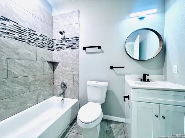 a bathroom with a toilet a sink a mirror and bathtub