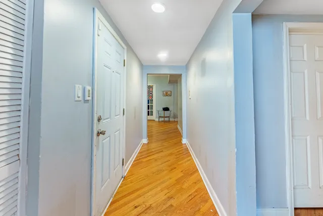 a view of a hallway with wooden floor and a bathroom