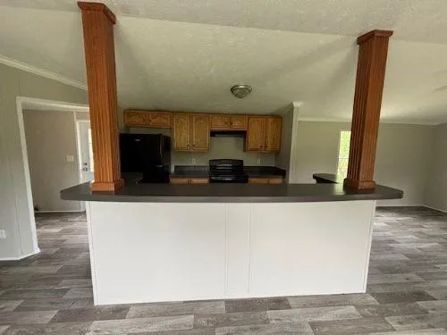 a living room with stainless steel appliances kitchen island granite countertop a refrigerator a stove and a sink with wooden floor