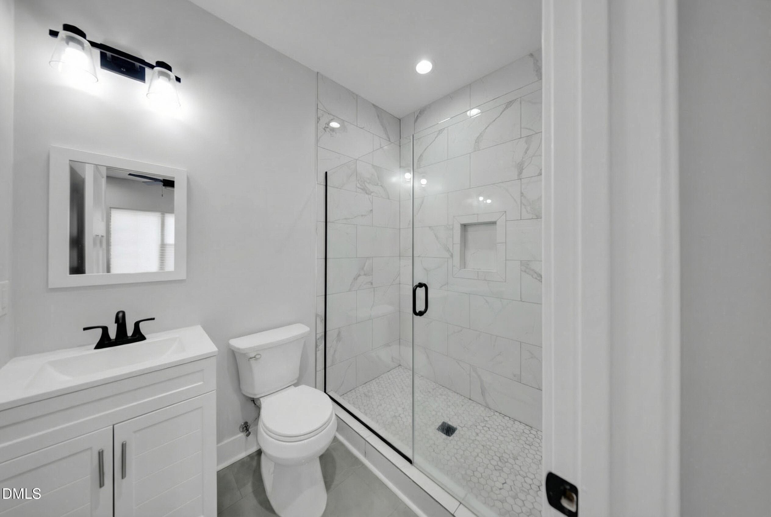 3908 Booker Avenue Durham, NC 27713 - Photo 55 of 71 a bathroom with a toilet a sink a mirror and shower