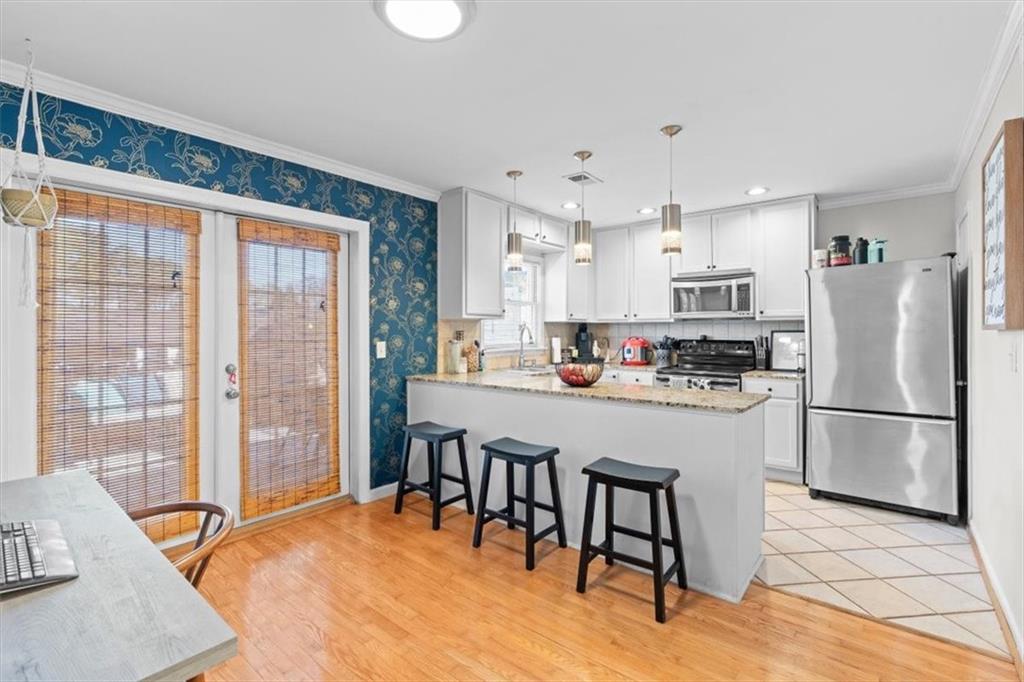 1101 Collier Road Northwest, Unit T5 Atlanta, GA 30318 - Photo 10 of 32 a kitchen with stainless steel appliances granite countertop a refrigerator a microwave oven a sink a dining table and chairs with wooden floor