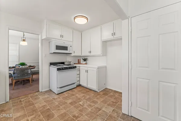 a kitchen with granite countertop white cabinets and white appliances