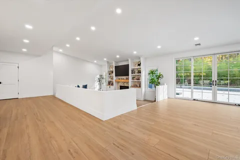 a view of an empty room with wooden floor and windows