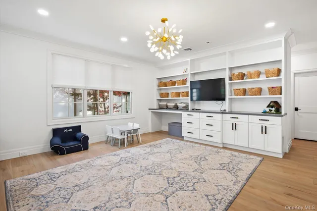 a large white kitchen with stainless steel appliances kitchen island granite countertop a stove a sink dishwasher and a flat screen tv