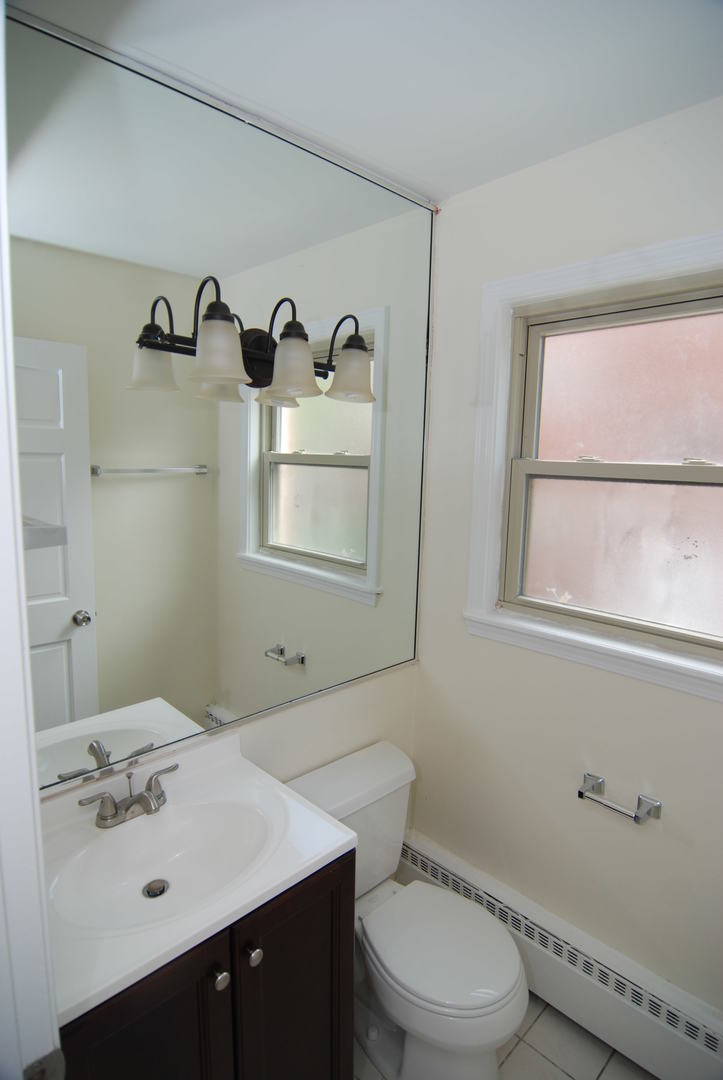 7530 North Ridge Boulevard, Unit 2E Chicago, IL 60645 - Photo 12 of 15 a bathroom with a sink vanity mirror and toilet