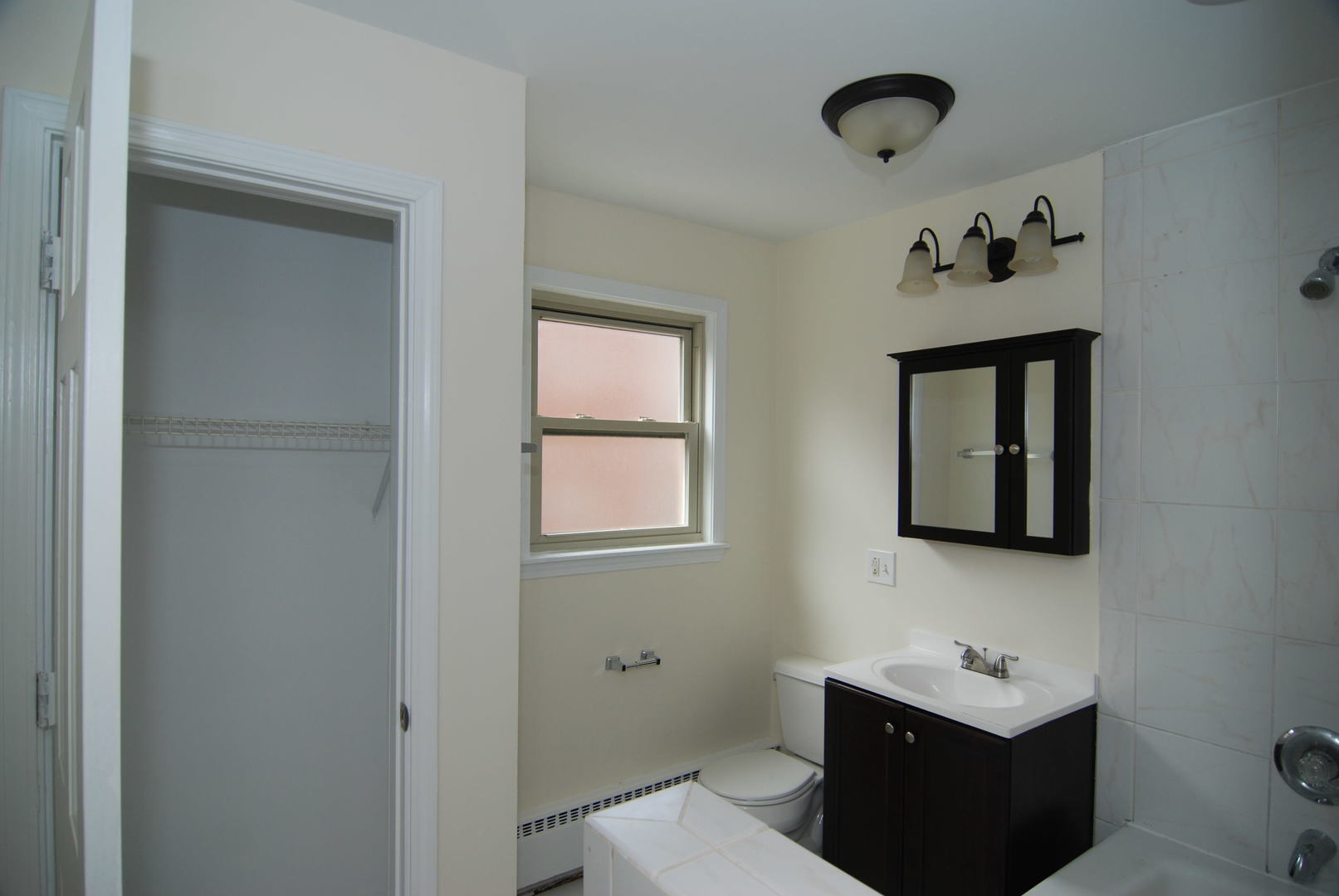 7530 North Ridge Boulevard, Unit 2E Chicago, IL 60645 - Photo 14 of 15 a bathroom with a toilet sink and mirror