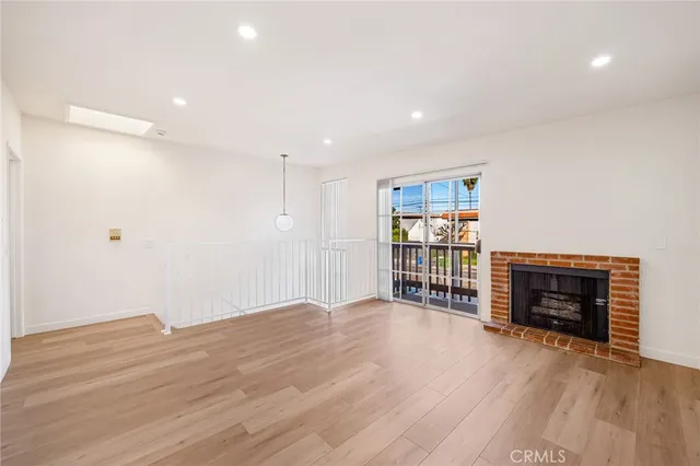 a view of an empty room with wooden floor and a fireplace