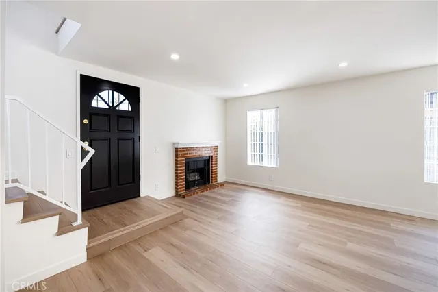 an empty room with wooden floor fireplace and windows