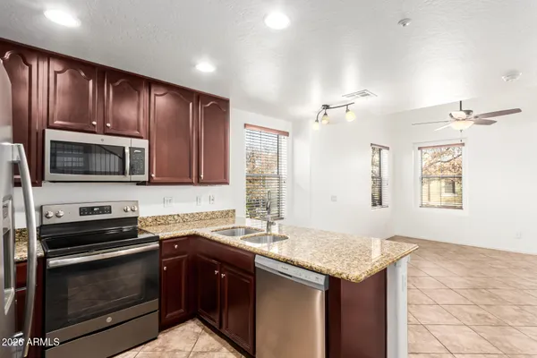 a kitchen with granite countertop wooden cabinets a stove top oven a sink and dishwasher