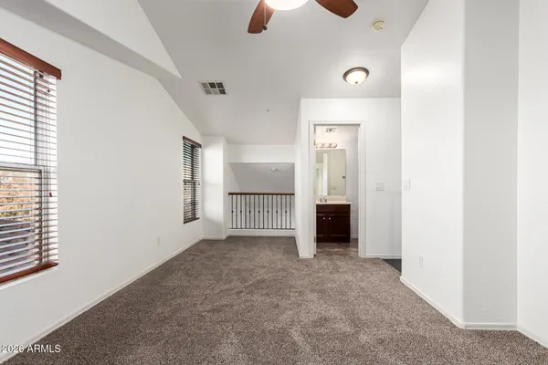 an empty room with chandelier fan and windows