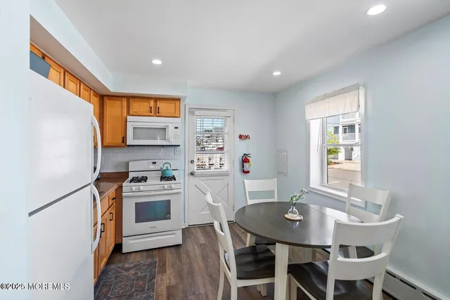 a kitchen with stainless steel appliances granite countertop a stove a sink a microwave a refrigerator a dining table and chairs with wooden floor