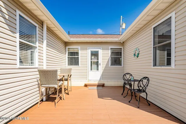 a view of a patio with table and chairs with wooden floor and fence