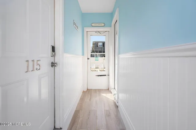 a view of a hallway with wooden floor and a bathroom