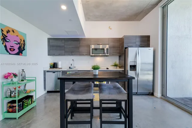 a kitchen with stainless steel appliances a table chairs and refrigerator in it