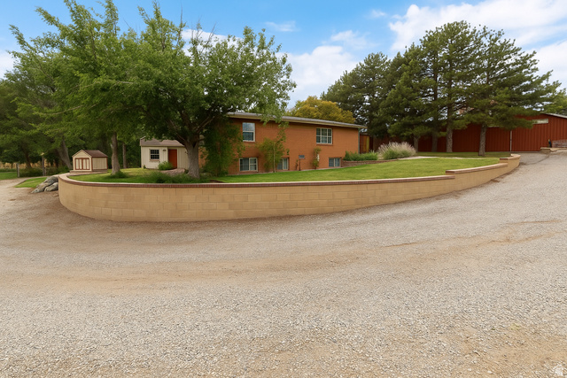 16535 South Redwood Road Riverton, UT 84065 - Photo 38 of 59 Brick exterior residence with a gravel driveway, retaining wall, and mature trees