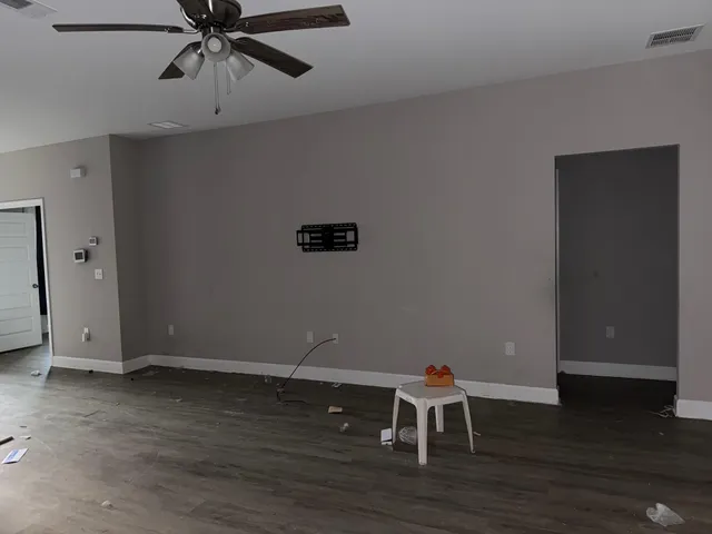 a view of a room with wooden floor and ceiling fan