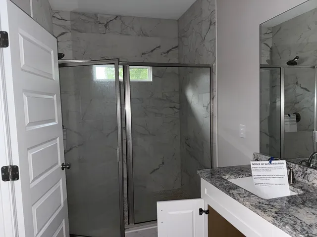 a bathroom with a granite countertop shower and a sink