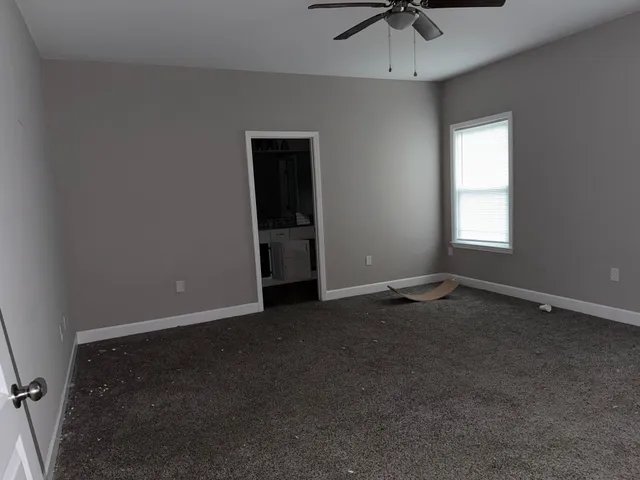 an empty room with a chandelier fan and windows